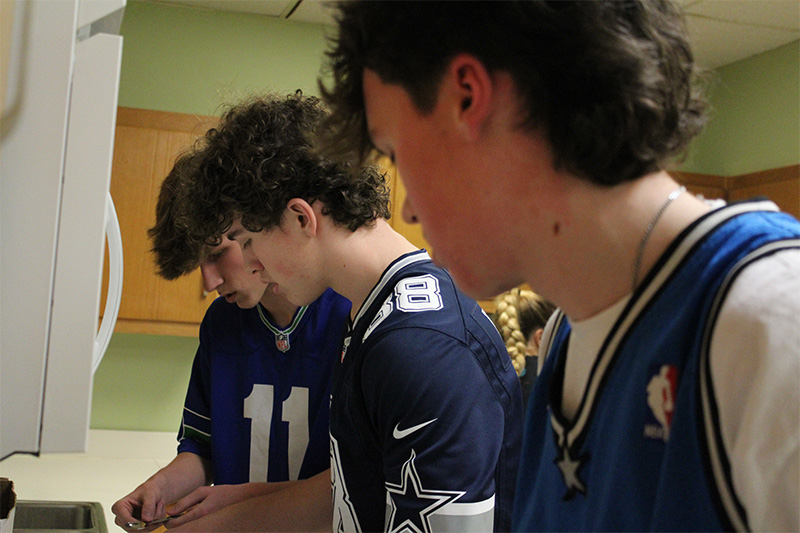 3 male students cooking as part of the amazing race challenge